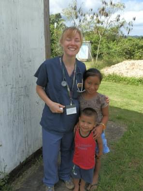 Tess MacQueen with children during Pine Point Medical global mission trip, providing care in remote communities.