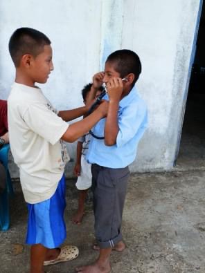 Local children sharing glasses during Pine Point Medical mission trip in a remote community.