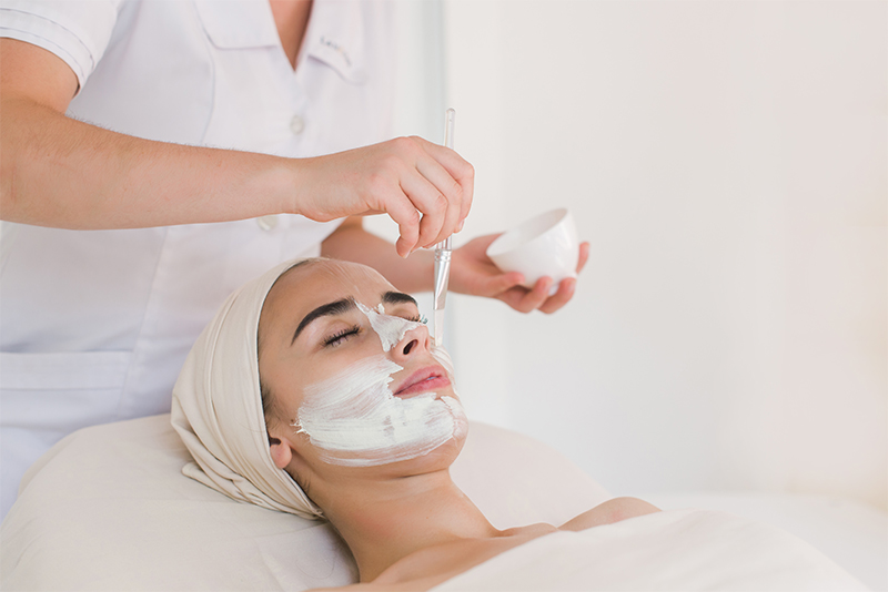 Woman receiving a medical-grade facial peel treatment applied with a brush for smoother, brighter skin